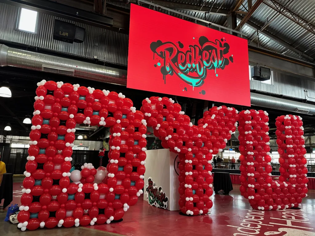 10-foot tall custom balloon letters spelling “DYU” in red, white, and teal displayed at a back to school event  in St. Louis.
