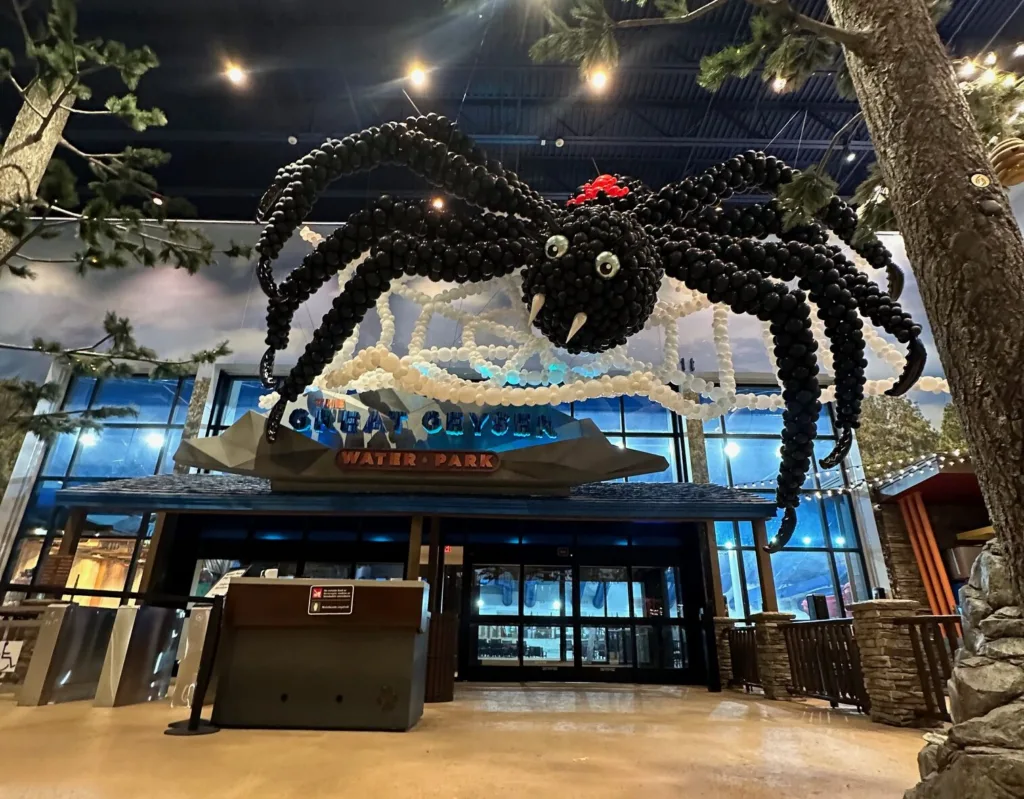 Massive black balloon spider with red accents suspended in a giant white balloon web over an entrance- done by St. Louis Balloon Artist from Party Perks.