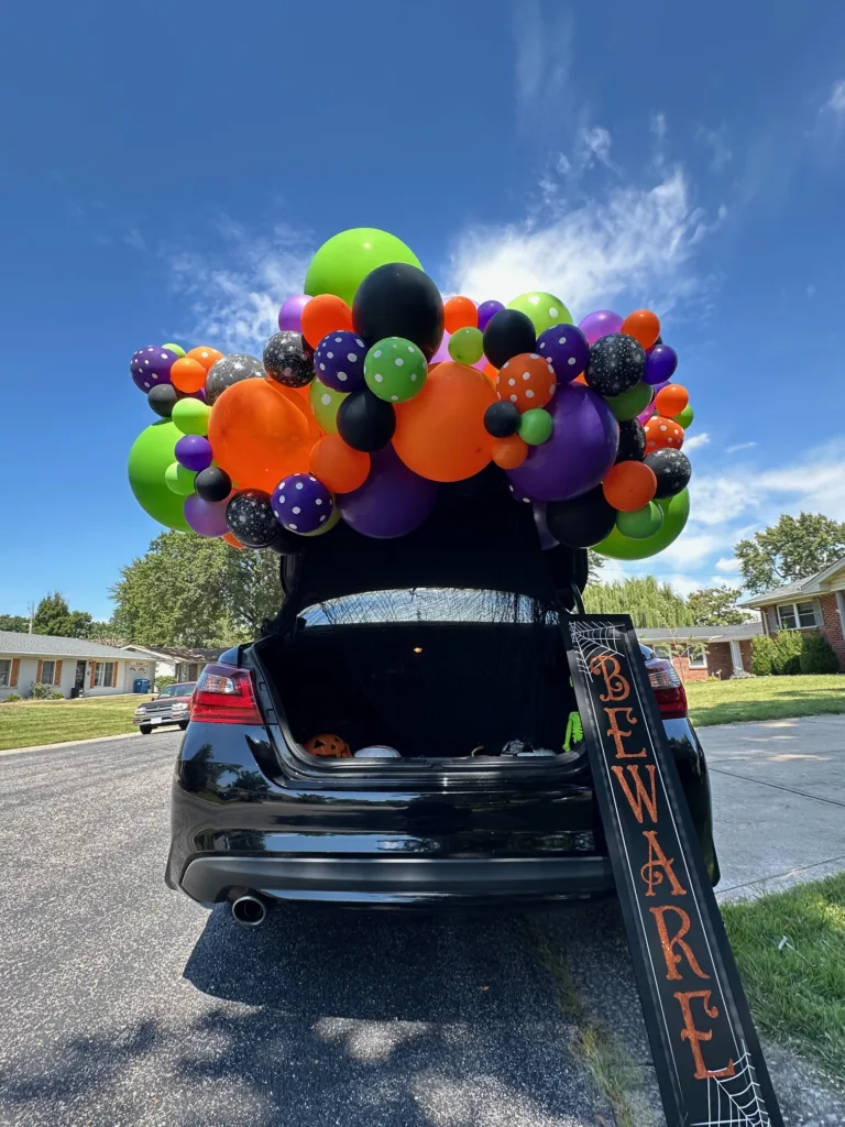 Colorful Halloween balloon garland with orange, black, purple, and green balloons decorating a car trunk for a Trunk or Treat event in St. Louis.