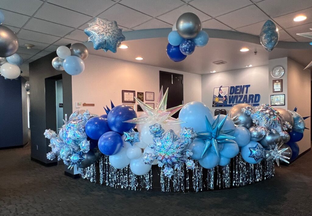Winter Wonderland corporate lobby balloon décor in silver, blue, and white — elegant balloon design by Party Perks STL for Dent Wizard.