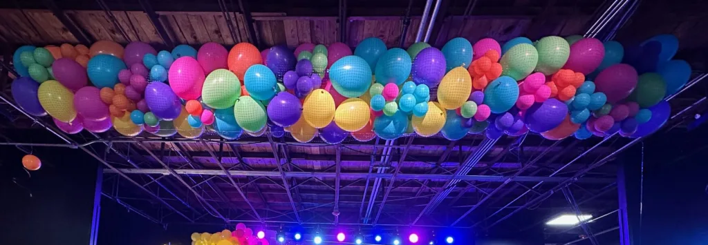 New Year’s Eve balloon drop installation over a stage with colorful balloons ready for a midnight countdown in St. Louis.