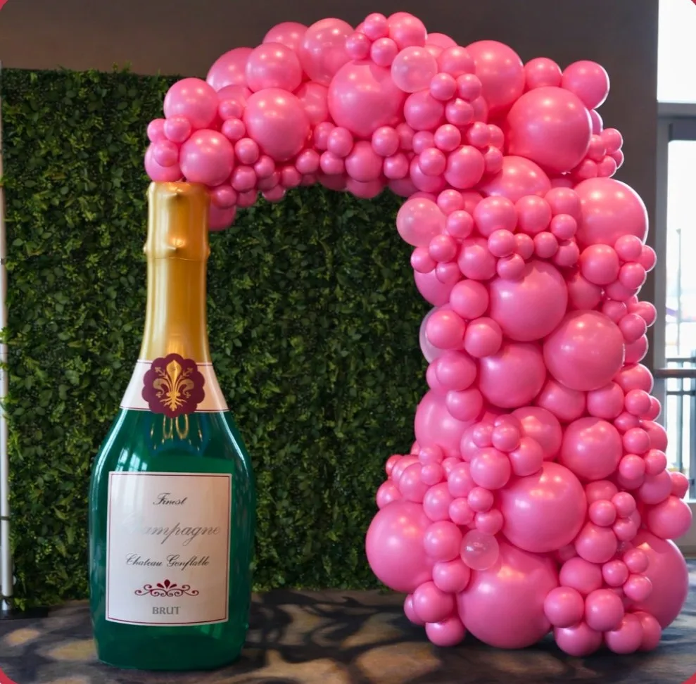 Luxury balloon styling by Party Perks featuring a pink organic balloon garland styled around a jumbo champagne bottle photo prop for a celebration in the St. Louis area.