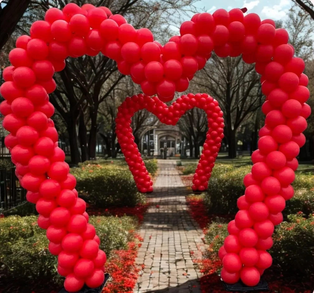 Luxury balloon styling by Party Perks featuring red heart-shaped balloon arches creating a romantic outdoor walkway installation for a Valentine’s event in St. Louis.