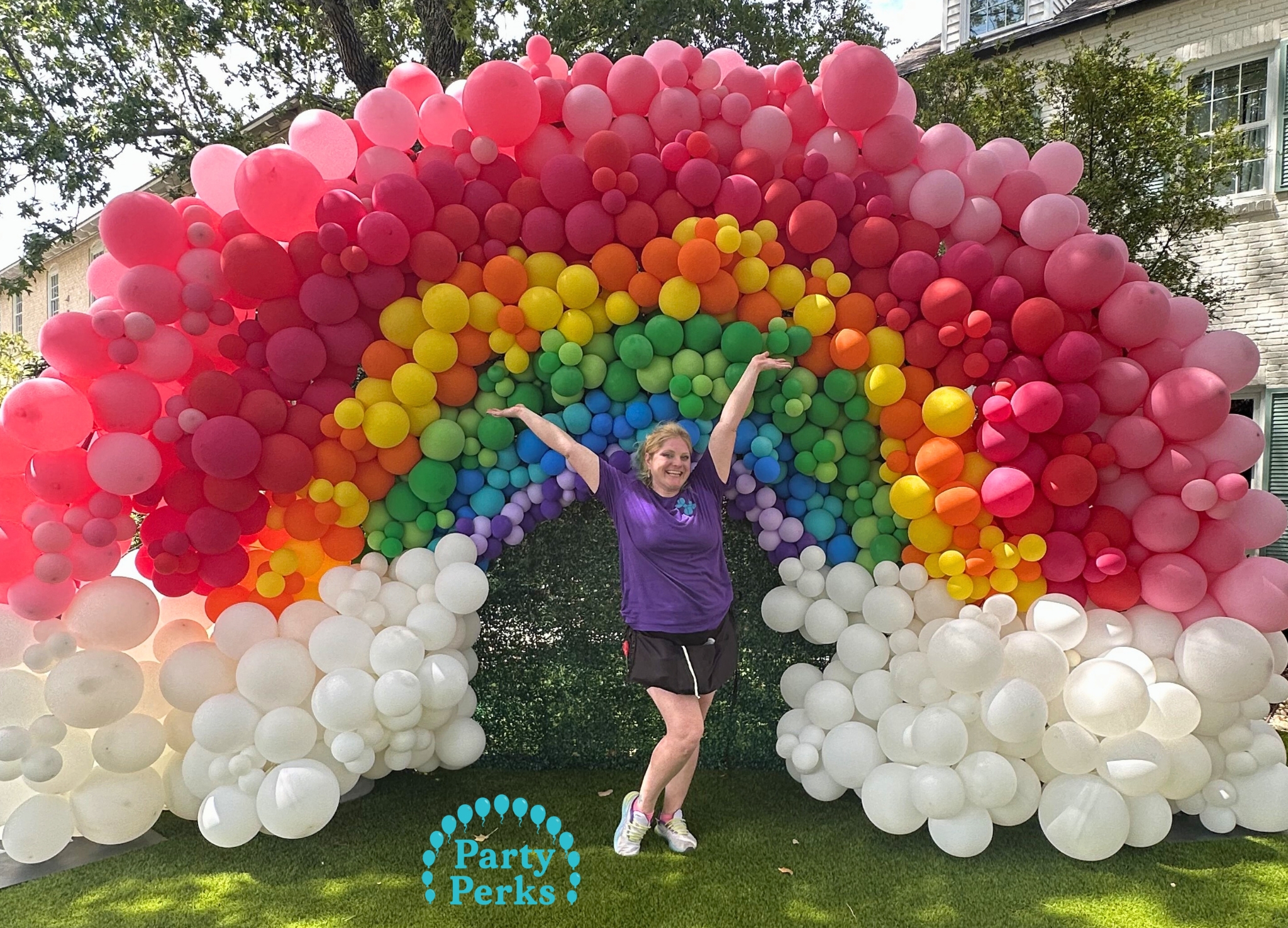 Balloon Rainbow Backdrop Colorful Easter balloon arch with rainbow design and white cloud balloons, created by a balloon decorator in Greater St. Louis, MO.