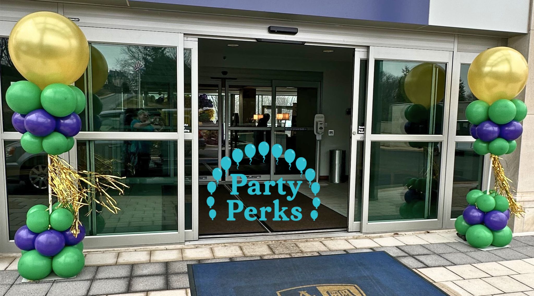 mardi-gras-balloon-towers-st-louis Mardi Gras balloon columns in purple, green, and gold decorating the entrance of a St. Louis event venue.